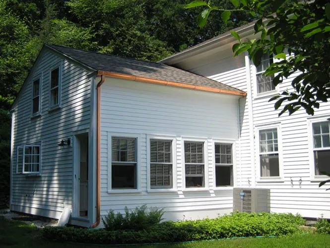 Rear addition with copper flashing joined to an existing white farmhouse