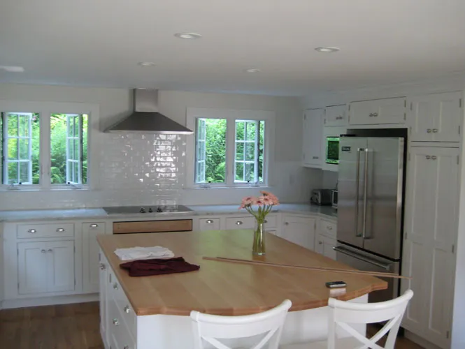 Remodelled white kitchen with a butcher-block island and subway tile backsplash