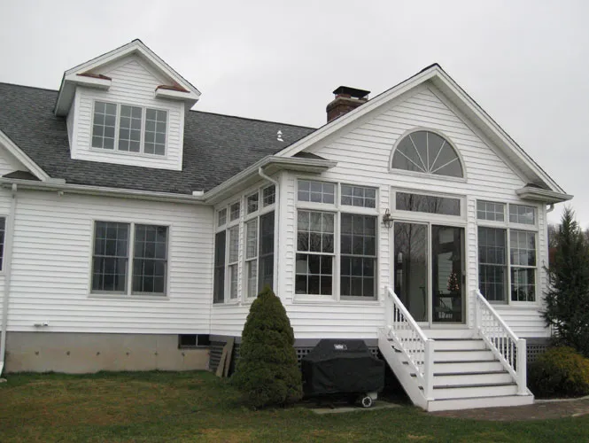 Sun room and rear addition with a gable window on a white clapboard house